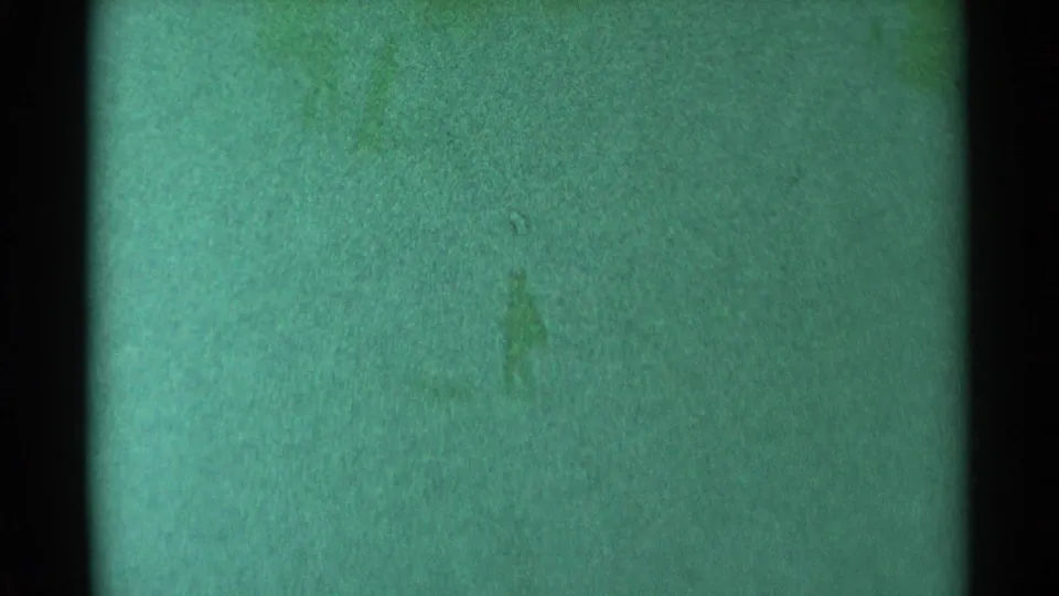 Final 1959 South Dakota 8mm frame remains abstract, with green tint, soft grain, dark borders, and faint smudges but no visible people.