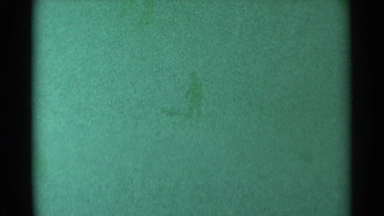 Distant dark figures on a green-tinted snowy slope.