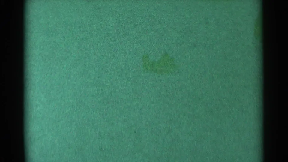 A 1959 South Dakota 8mm home-movie frame with green cast, visible grain, and faint marks that do not resolve into people or sleds.