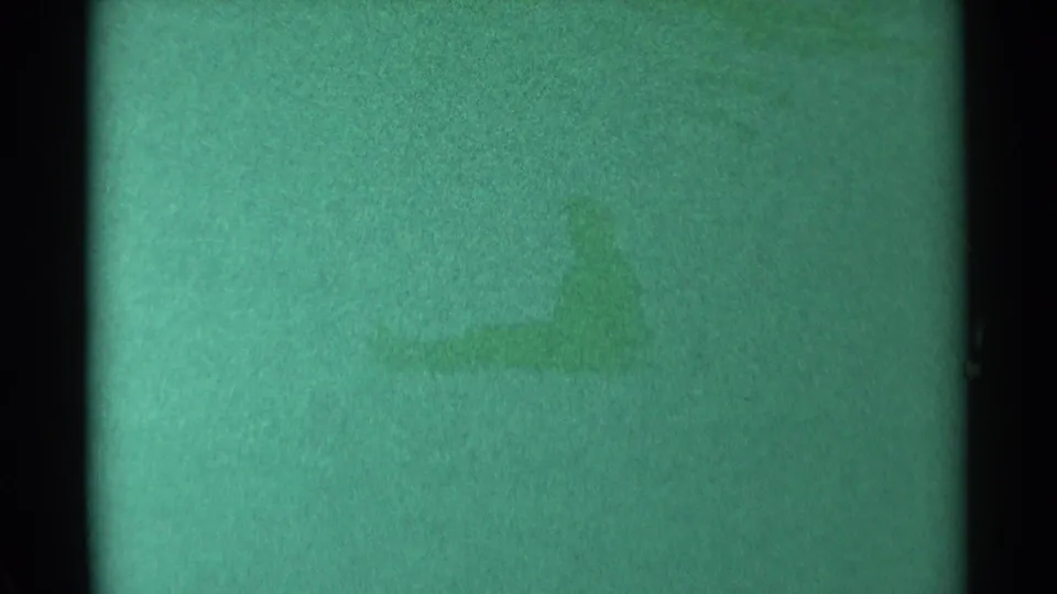 The sledder appears farther down the snowy hill in this green-tinted 1959 South Dakota 8mm frame.
