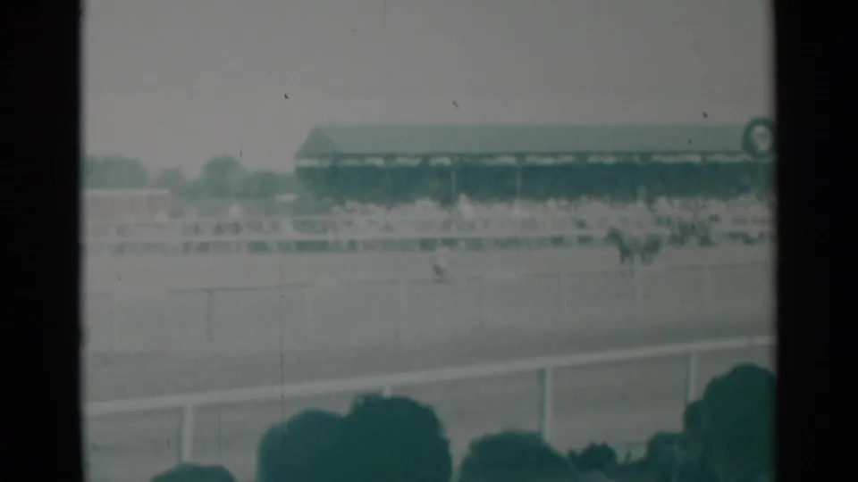 1960 Cheyenne, Wyoming rodeo scene from the stands, with distant riders in an arena and spectators filling the bleachers.