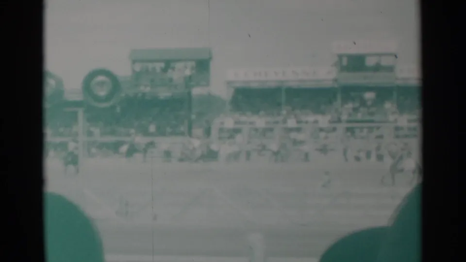 Spectator-shot 1960 Cheyenne rodeo frame with arena fencing, grandstands, and a large circular object near the edge.
