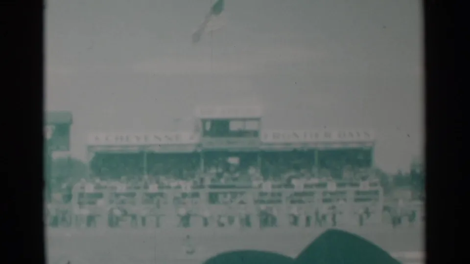 Cheyenne Frontier Days grandstand area with spectators and riders visible across the arena under a pale sky.
