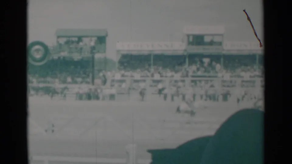 Cheyenne rodeo arena with visible Frontier Days signage, spectators, rail fencing, and a rider moving through the scene.