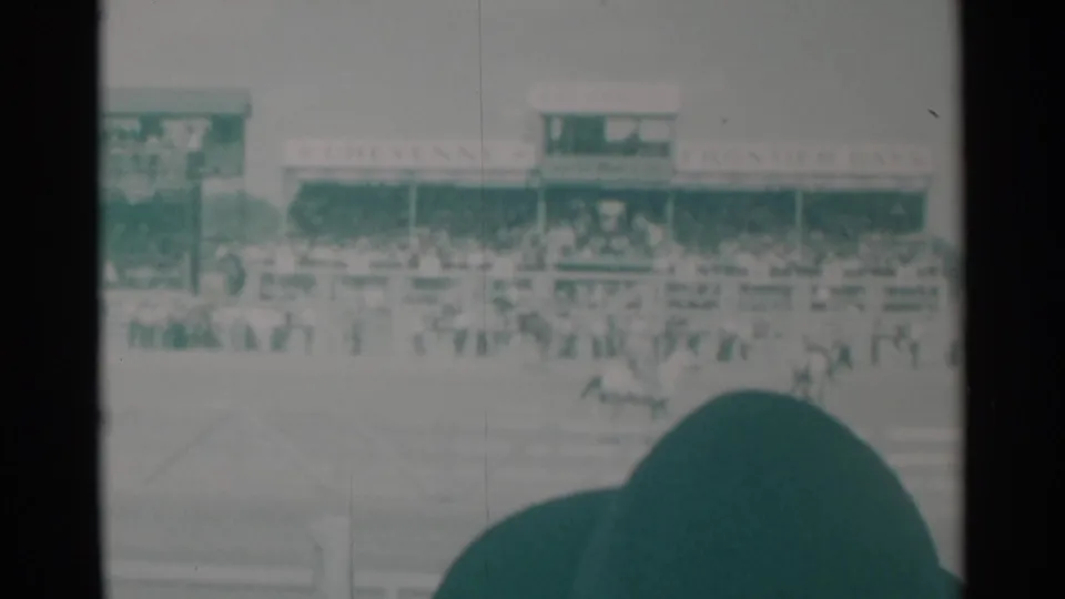 At the Cheyenne rodeo, a horse and rider move across the arena while the grandstand and Frontier Days signage remain visible behind them.