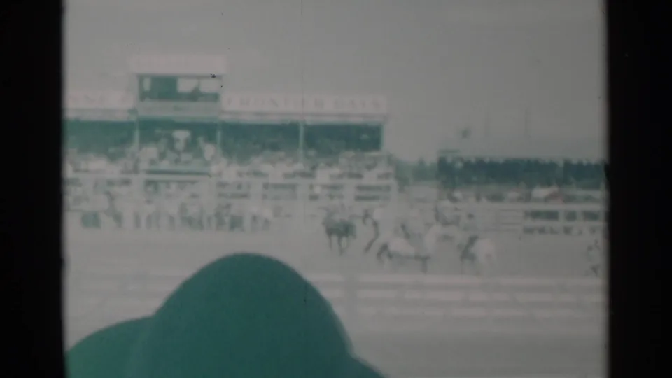 Cheyenne rodeo action continues near the rail, with a horse and rider in the arena and Frontier Days signage visible across the grandstand.