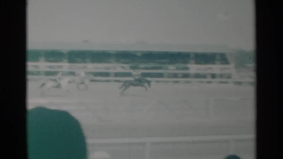 1960 Cheyenne, Wyoming frame with horses and riders spread across the arena before a long spectator grandstand.