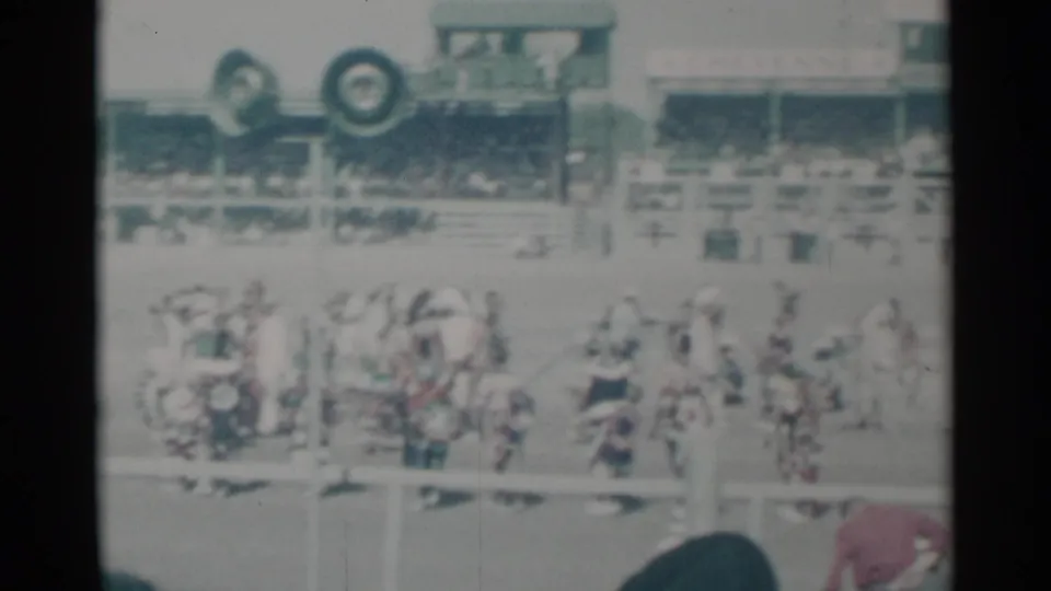 Participants in light clothing or costumes stand on a Cheyenne event field, with a packed grandstand behind them.