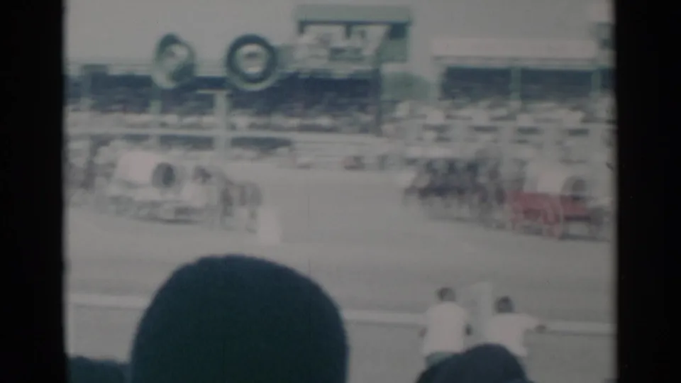 1960 Cheyenne rodeo footage showing horse-drawn chariots crossing the arena as spectators watch from the stands.