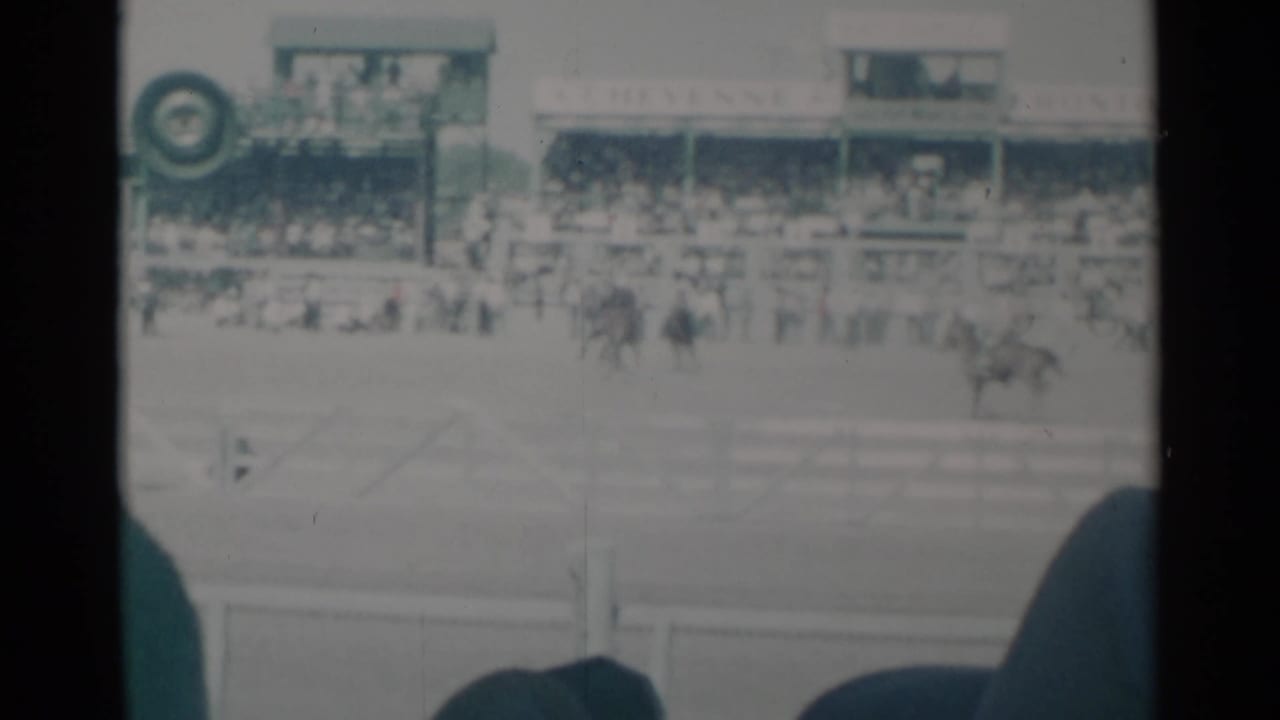 Rodeo arena with a horse and rider near grandstands and event signage.