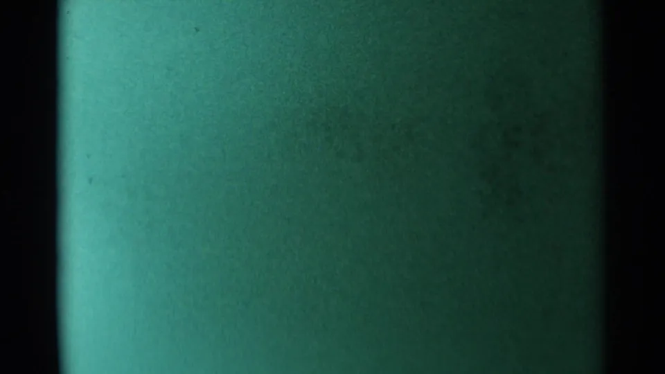 A green-tinted end frame or exposure shift shows film texture with minimal identifiable rodeo detail.