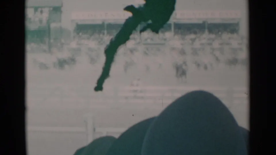 1960 home-movie view from the crowd at a Cheyenne rodeo, with spectators silhouetted beneath arena activity.