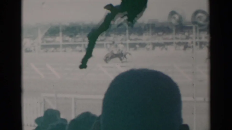 1960 8mm rodeo view with a bucking horse in the arena partly obscured by nearby spectators watching from the crowd.
