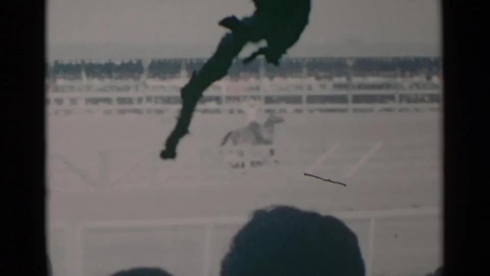 1960 Cheyenne 8mm frame of a jockey riding along the track, seen from the audience with soft focus and film grain.