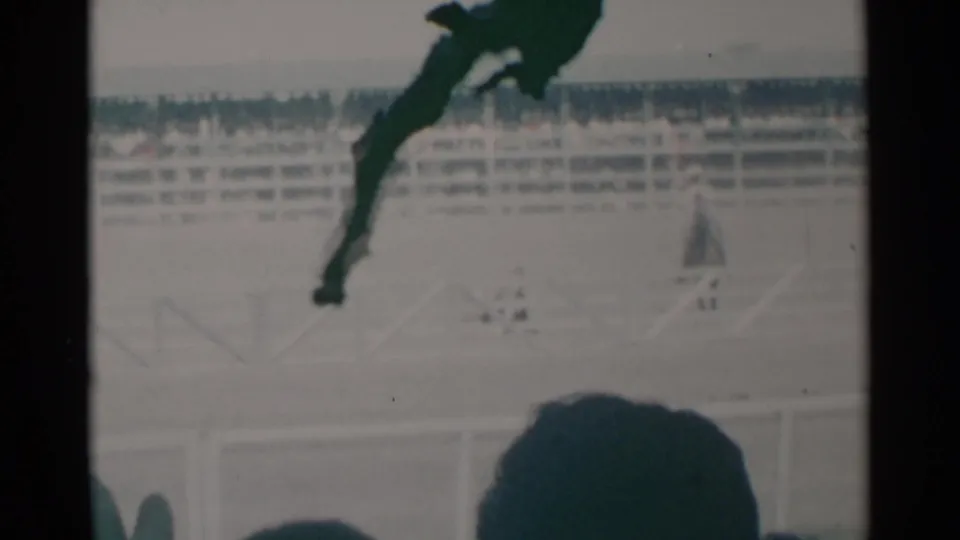 Cheyenne horse race frame from 1960 showing a silhouetted rider and horse beyond spectators in the stands.