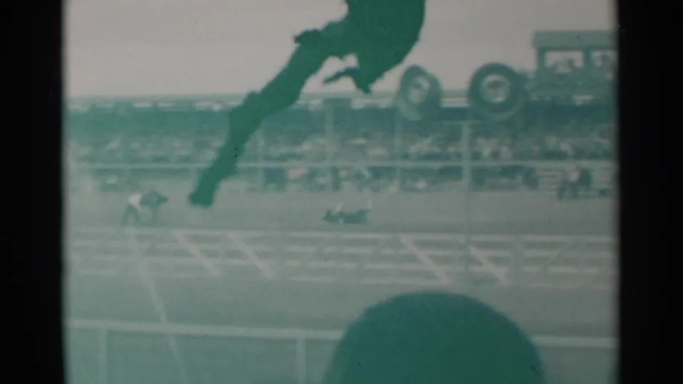 A 1960 Cheyenne rodeo frame shows arena rails, horseback activity, spectators in the stands, a parked vehicle near the arena edge, and the same green-tinted 8mm texture.