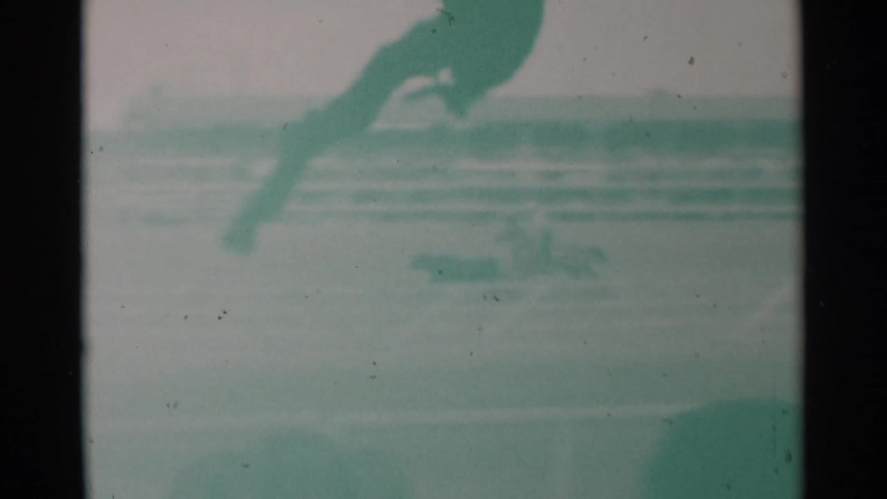 Blurred horse and rider crossing a rodeo arena with bleachers behind.