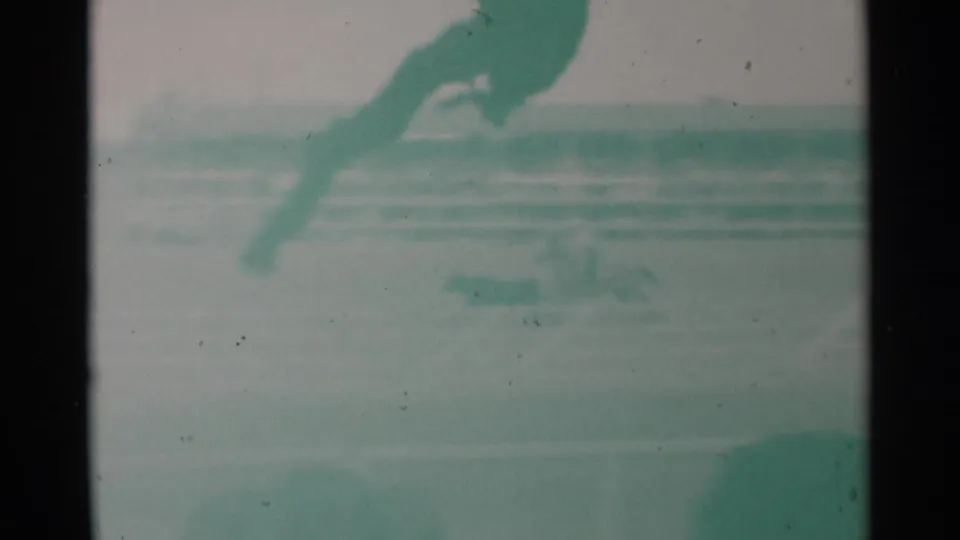 1960 Cheyenne rodeo home-movie frame showing a horse and rider moving quickly across an arena before distant spectators.