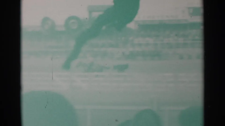 Faded 8mm frame from the Cheyenne rodeo clip with a horse and rider entering the upper frame above arena rails and stands.
