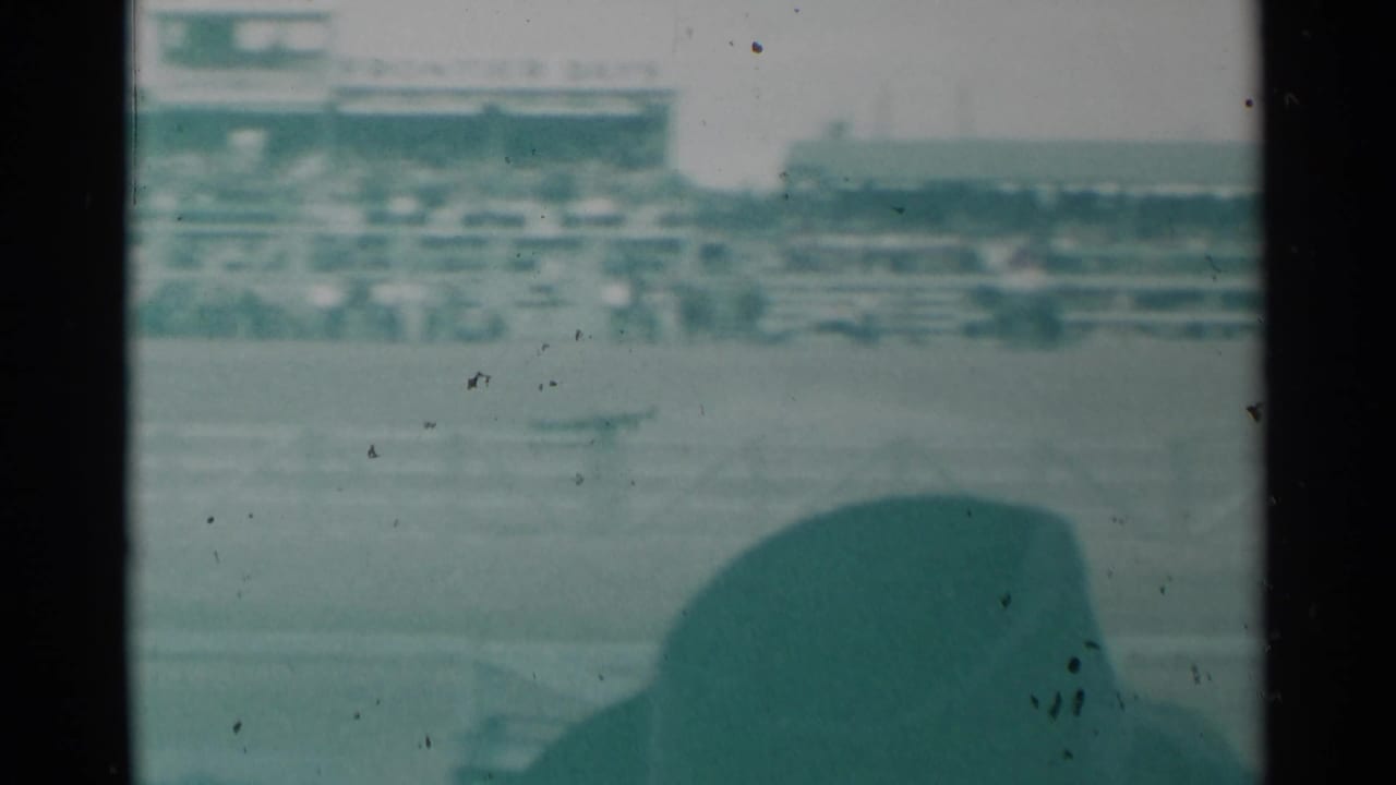 Distant rodeo arena and grandstand seen from behind spectators.