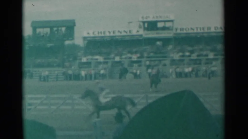 1961 Cheyenne rodeo footage showing a horse and rider near the rail with Frontier Days signage across the grandstand.