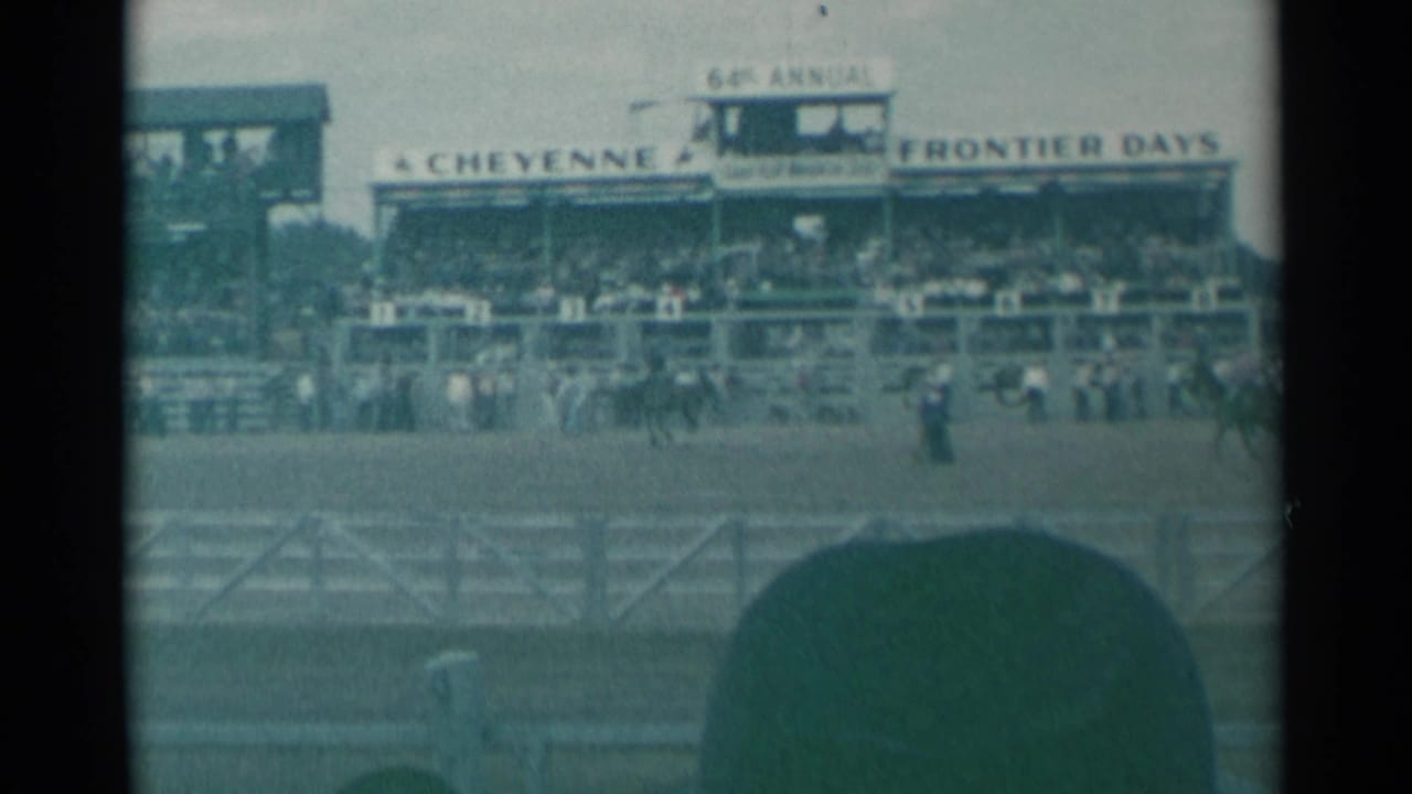 1961 Cheyenne, Wyoming rodeo view from the stands, with riders in the arena and the Cheyenne Frontier Days sign above spectators.