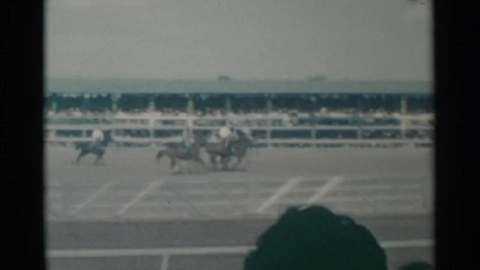 1961 Cheyenne rodeo footage shows riders grouped in the arena, with stands behind them and a foreground spectator shape at the lower edge.