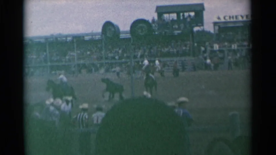 1961 Cheyenne rodeo scene with horseback riders in a dusty arena, spectators in hats, grandstand seating, and partial Cheyenne signage.