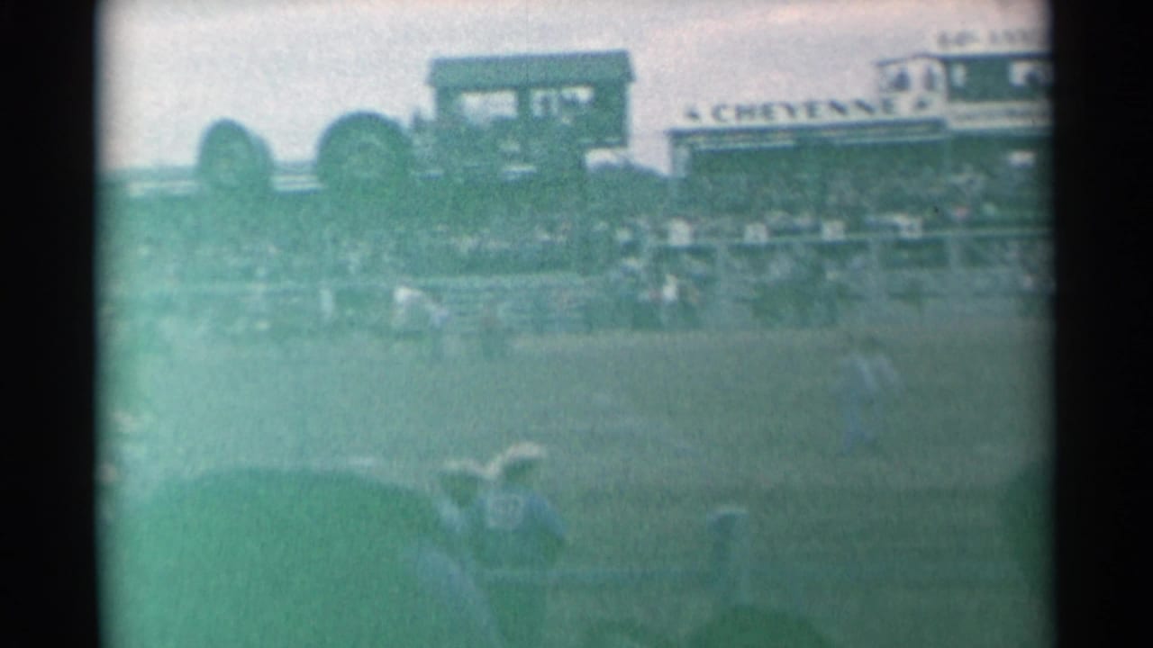 Rodeo arena with horseback riders, bleachers, and a CHEYENNE sign in the background.