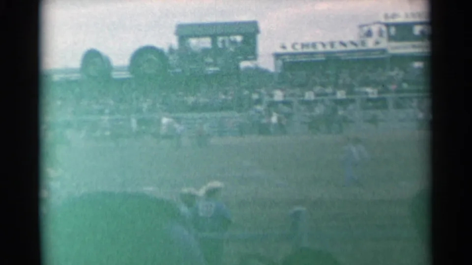 1961 Cheyenne, Wyoming rodeo scene with riders in an arena, spectators in bleachers, and a CHEYENNE sign above the stands.