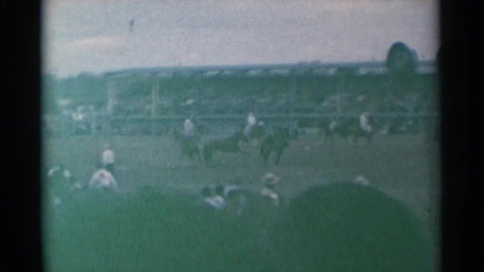 Wide 1961 Cheyenne rodeo view with horseback riders moving across the arena as spectators watch from the stands.
