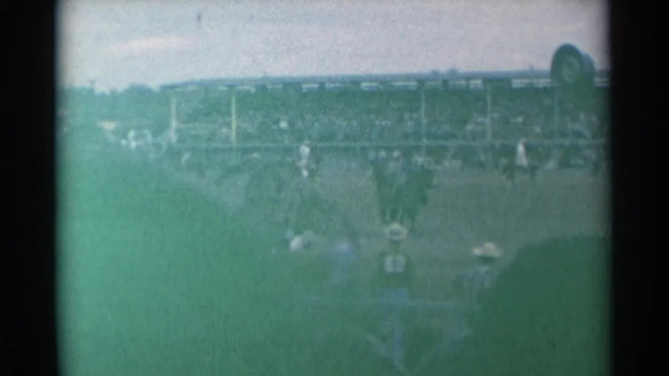 1961 Cheyenne rodeo arena seen from the stands, with riders and spectators partly obscured by soft green 8mm exposure.
