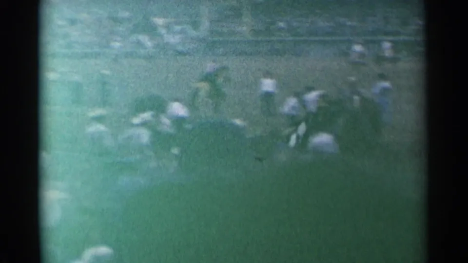 1961 Cheyenne rodeo action viewed from the stands, with riders and horses moving across a dusty arena in soft 8mm color.
