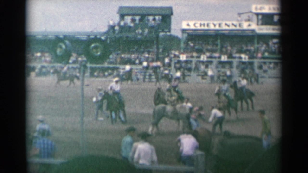 Riders on horseback gather in a rodeo arena before crowded grandstands.