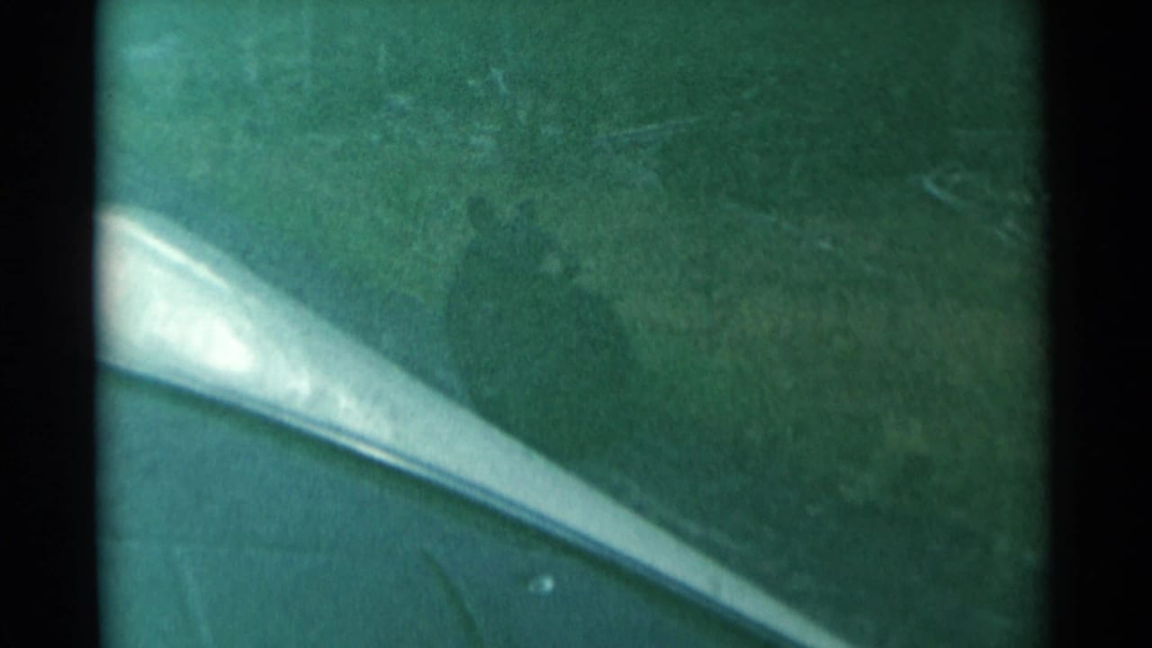 Car window and green-tinted glass with snowy terrain faintly visible beyond.