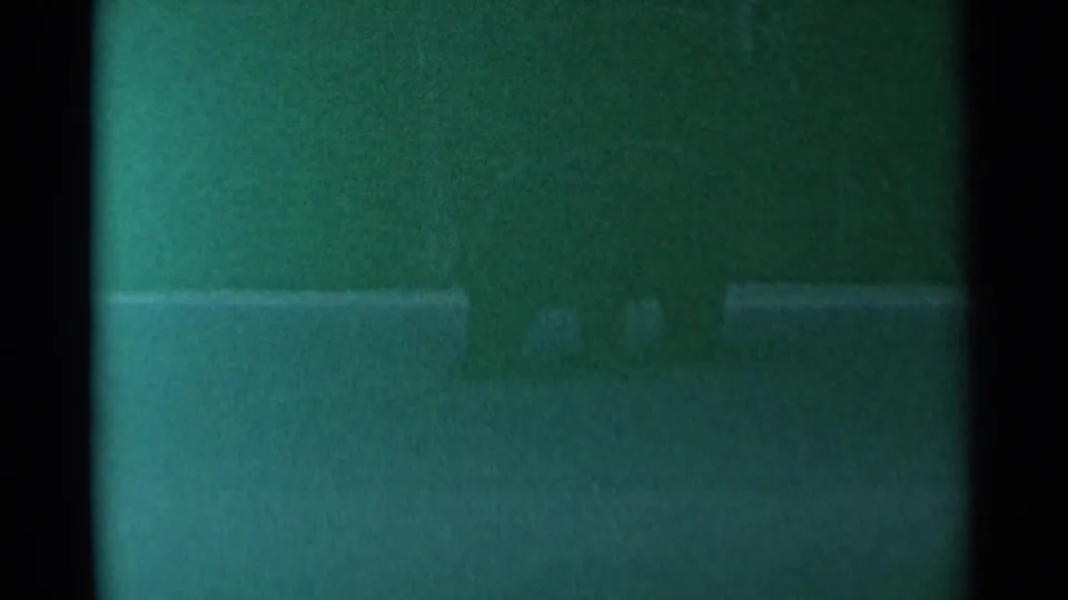 1961 Cheyenne 8mm frame with heavy grain, green cast, and a dim outdoor field where the subject is not clearly defined.