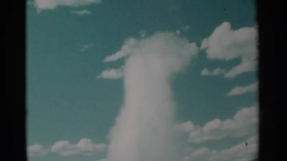 The geyser spray softens into a bright plume against a blue sky in this 1961 Wyoming home-movie frame.