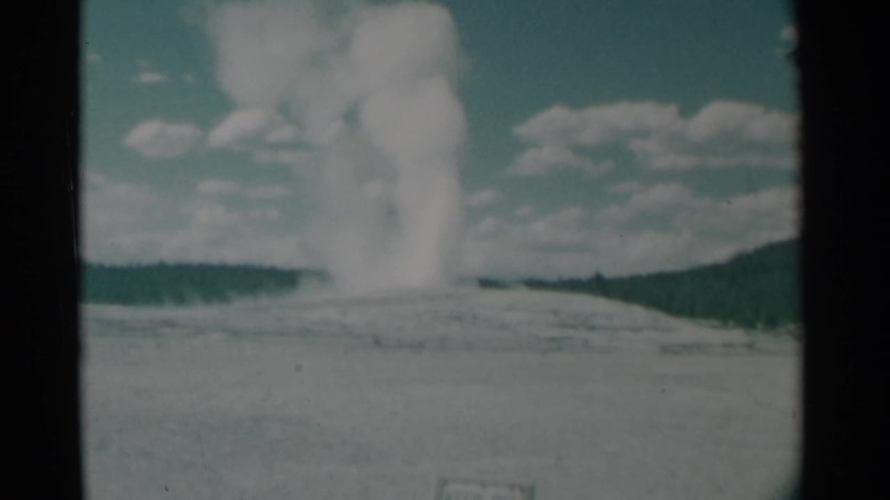 Large smoke column spreading upward above a low horizon and distant ridge.