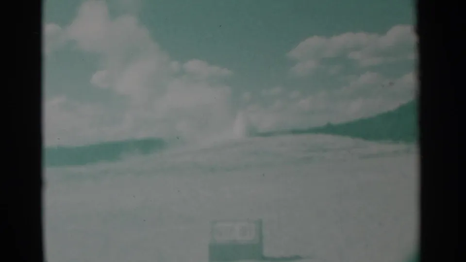The smoke disperses across the horizon in a faded 1961 8mm view, with a small sign-like object visible near the lower frame.