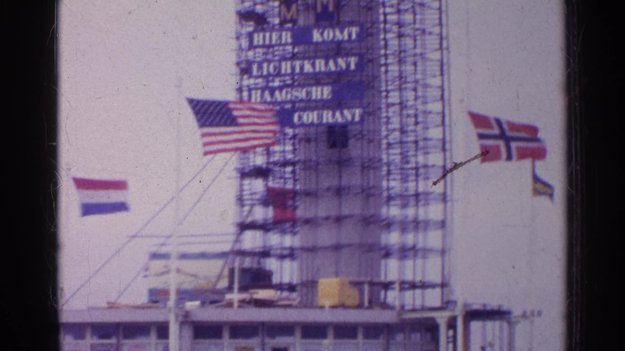 1961 shipboard frame showing scaffolding, a readable Haagsche Courant sign, and international flags in the wind.