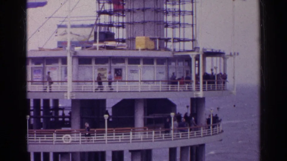 1961 Germany waterfront pier with open decks, people at railings, scaffolding, and water below.