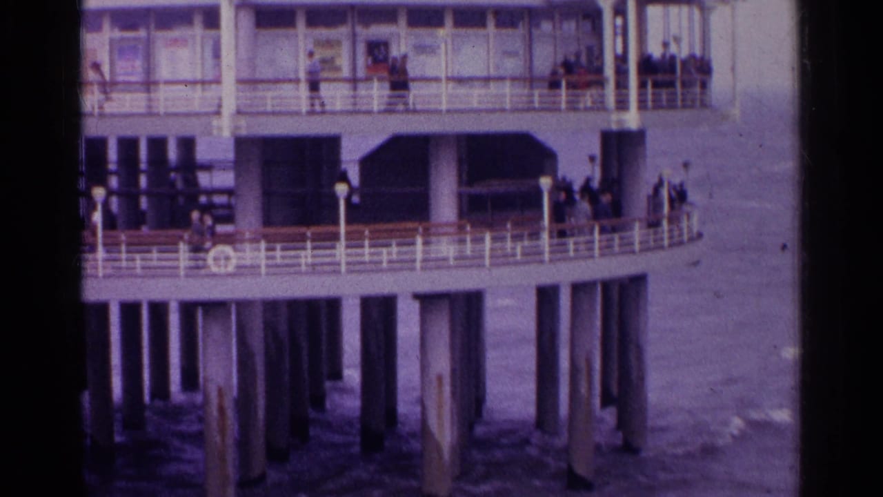 Pier deck over water with people near railings and support pillars below.