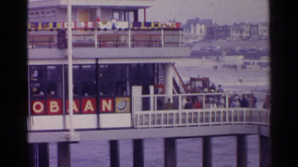 1961 Germany waterfront building showing an AUTOBAAN sign, deck railings, people, flags, and distant shoreline.