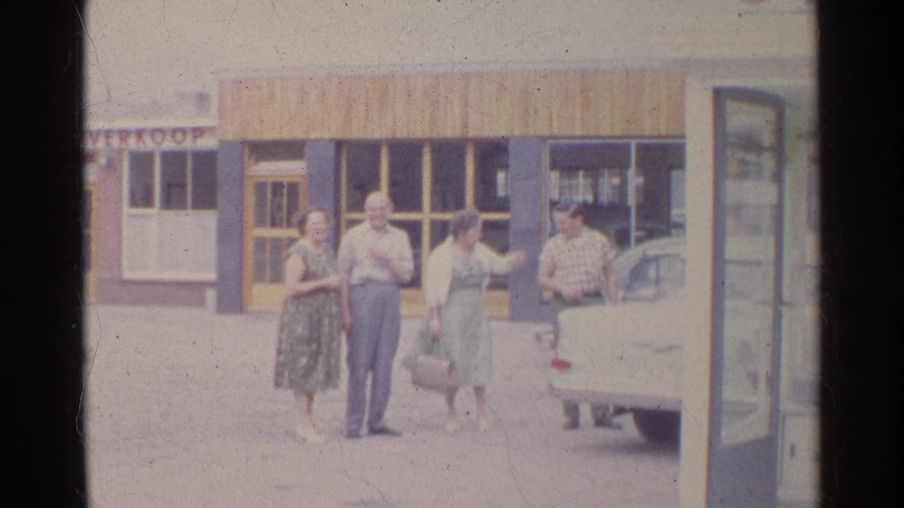 A woman gestures toward a man beside the car while the other adults look on in this 1961 Germany street scene.