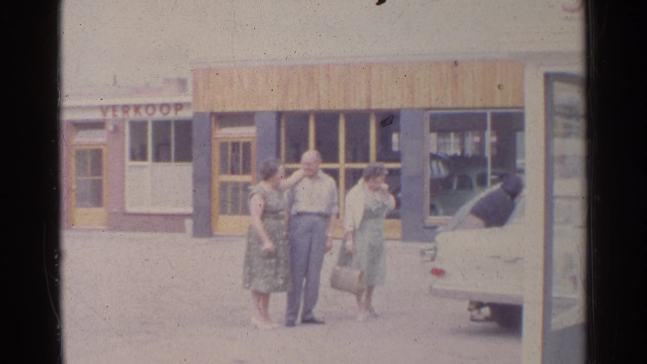 Adults outside a German storefront in 1961, with a woman holding a handbag and another man bent into a white car.