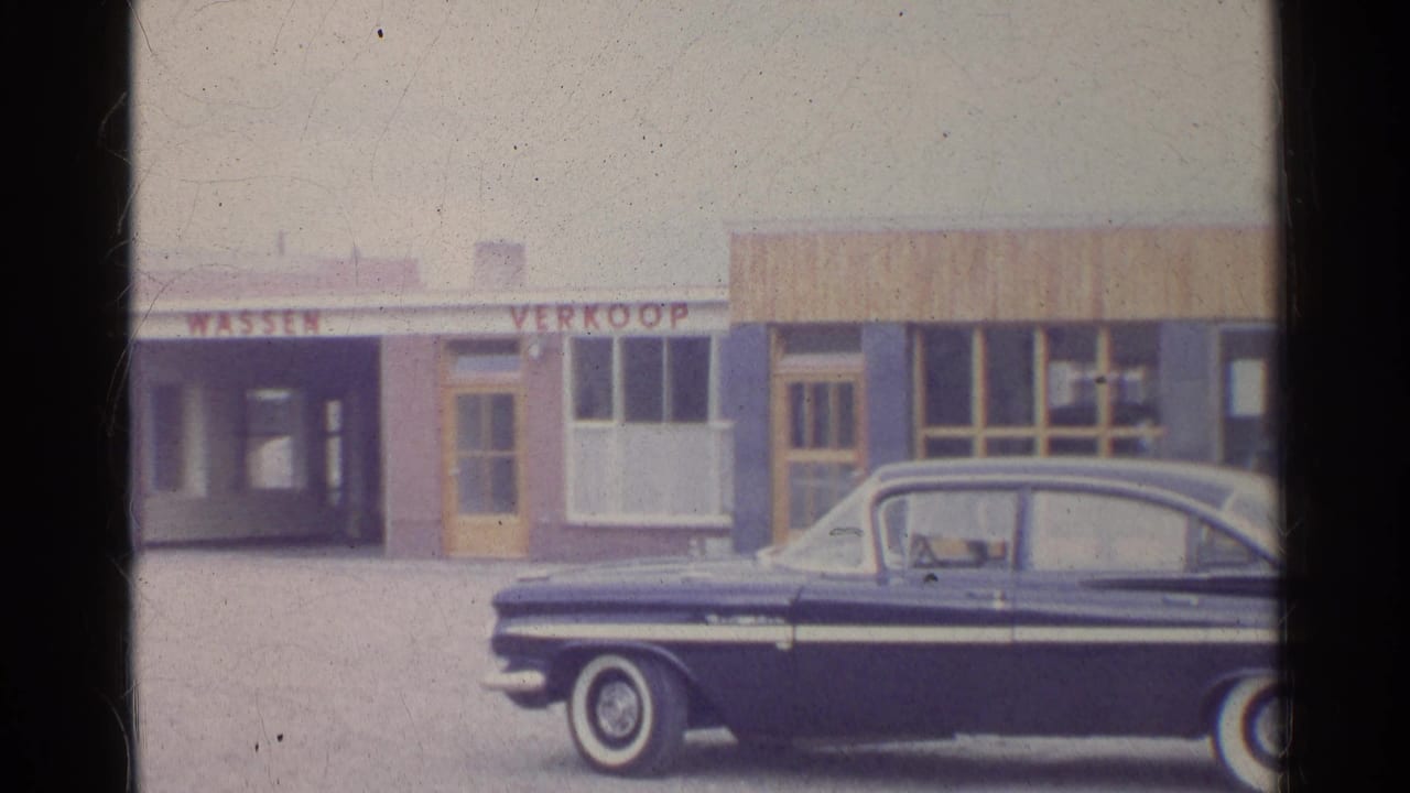 1961 Germany-labeled 8mm frame with a cropped dark sedan in the foreground of storefronts marked WASSEN and VERKOOP.