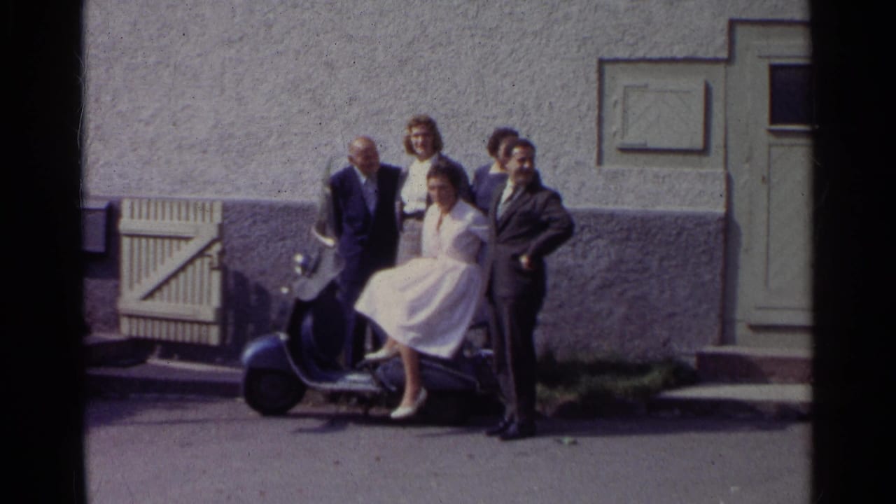 Adults pose around a blue scooter outside a textured building.
