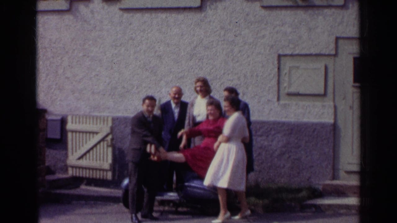 In 1961 Germany, the group continues a playful pose around the scooter, with the red-dressed woman balanced near the seat and others gathered close.
