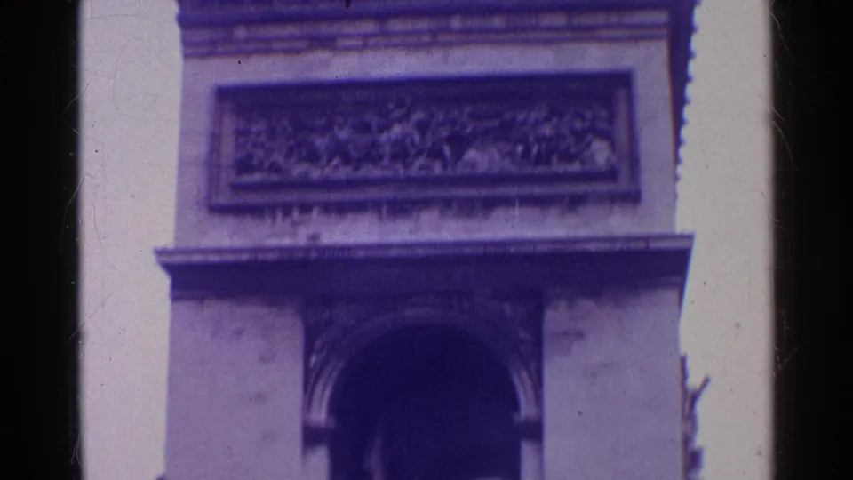 1961 Paris 8mm frame with the Arc de Triomphe centered tightly, showing the arch opening, upper carved panel, cornice, and soft purple cast.