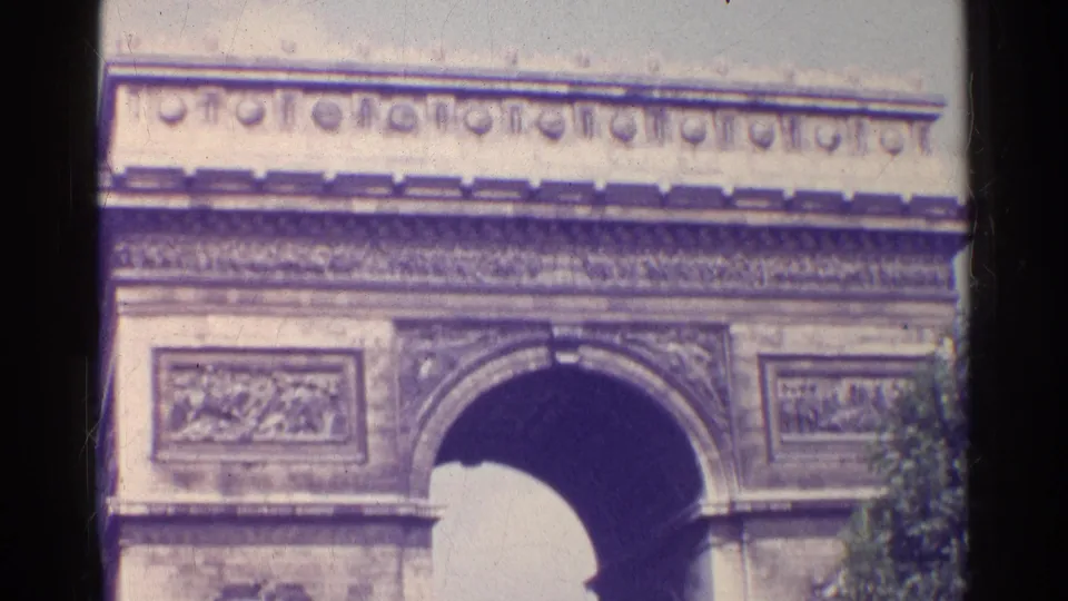 1961 Paris home-movie view of the Arc de Triomphe with the upper facade, central arch, and carved panels in soft focus.